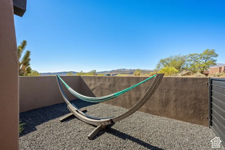 Private courtyard featuring stucco perimeter walls, dark decorative gravel ground cover, and mountain horizon scenery