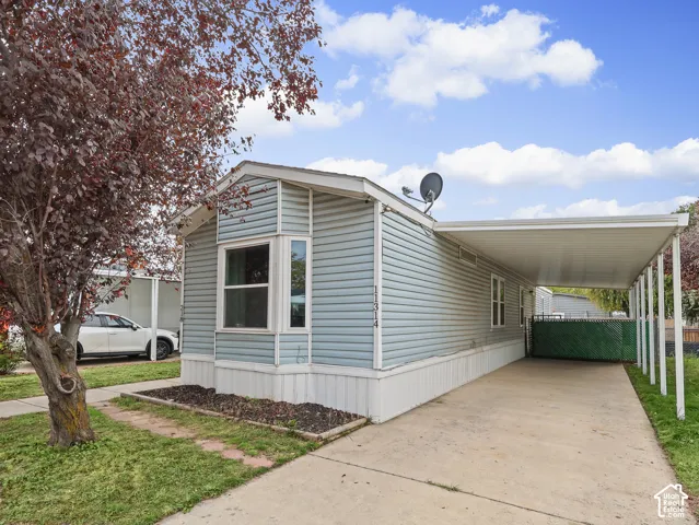 Light blue horizontal siding, bay window, concrete driveway, and covered carport
