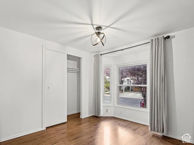 Bay window with exterior scenery, wood-finish flooring, and orb-style metallic light fixture