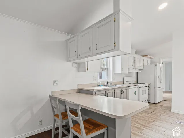 Kitchen area featuring white cabinetry, a built-in peninsula, neutral solid-surface countertops, and wood-finish flooring