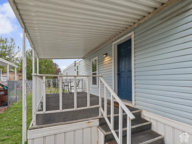 Covered porch featuring a metal canopy, metal railing, steps, and exterior wall-mounted lighting