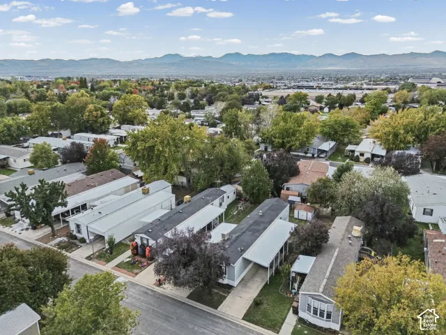 Aerial view of residential property featuring a paved driveway, attached carport, and mountain range backdrop