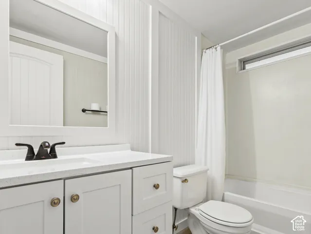 Bathroom  #2 featuring white beadboard wall paneling, a vanity with a solid-surface countertop and integrated sink, a framed mirror, and a tub-shower combination