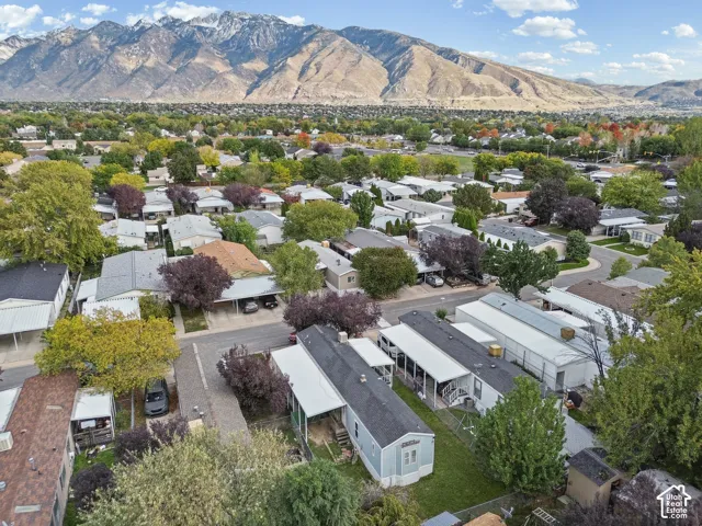 Aerial perspective featuring a landscape backdrop of mountain peaks, established mature trees, and paved thoroughfares