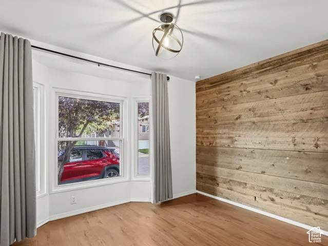 Wood-plank accent wall, bay window, wood-finish flooring, and geometric orb-style pendant light fixture