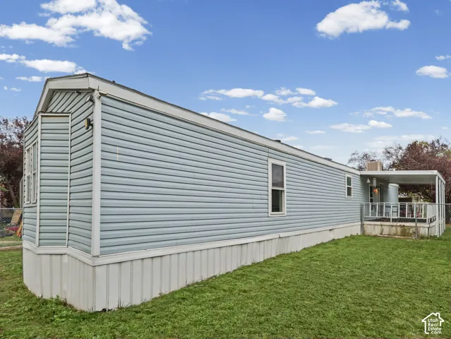 Light blue horizontal siding, bay window projection, covered porch area, and metal fencing