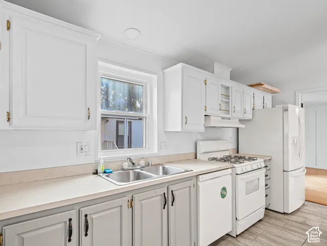 Kitchen featuring white upper cabinetry, grey lower cabinetry, dual-basin stainless steel sink, solid-surface countertops, and wood-finish flooring