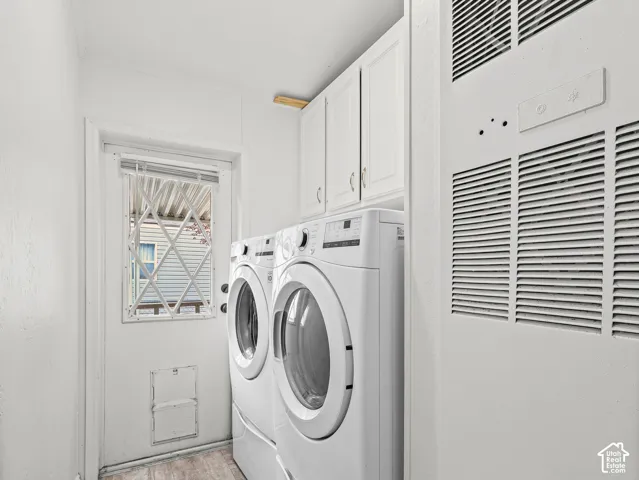 Laundry area featuring white shaker-style wall-mounted cabinetry, an exterior door with a security screen, and a wall-integrated climate control panel