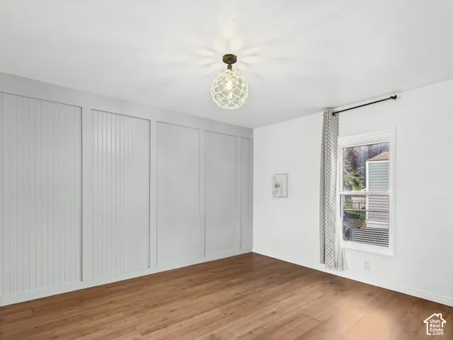 Paneled accent wall with wainscoting detail, wood-finish flooring, and a decorative orb-style light fixture