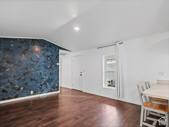Vaulted ceilings, wood-finish flooring, accent wall with decorative finish, single-hung window, and built-in counter surface