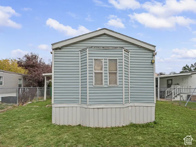 Light blue horizontal vinyl siding, dual vertical windows with a bay-style bump-out, and a neutral-toned vinyl skirting foundation