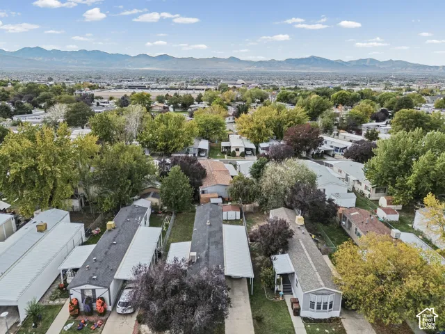 Aerial perspective featuring established tree canopy, paved driveways, covered parking structures, and mountain backdrops