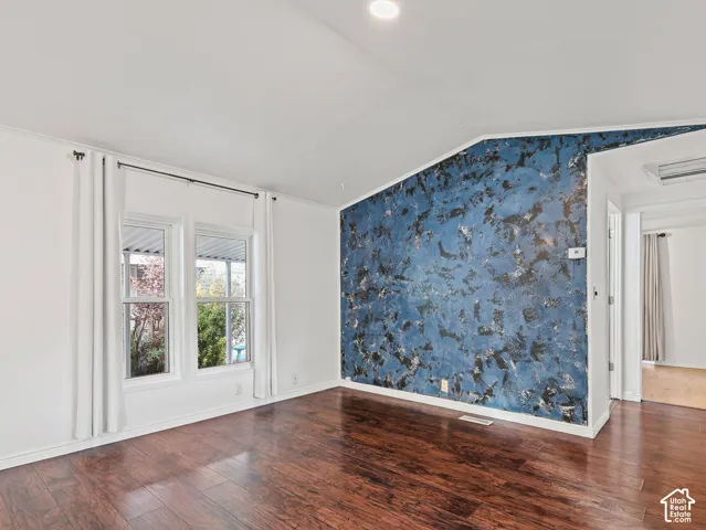 Vaulted ceilings, wood-finish flooring, recessed lighting, and a textured accent wall