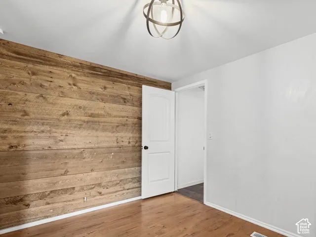 Accent wall featuring horizontal wood planking, wood-finish flooring, and a modern spherical metal orb pendant light fixture