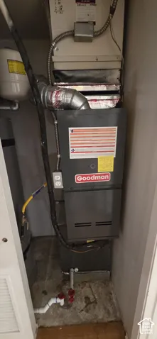 Goodman furnace unit featuring a metal exhaust vent, an expansion tank, and integrated utility connections