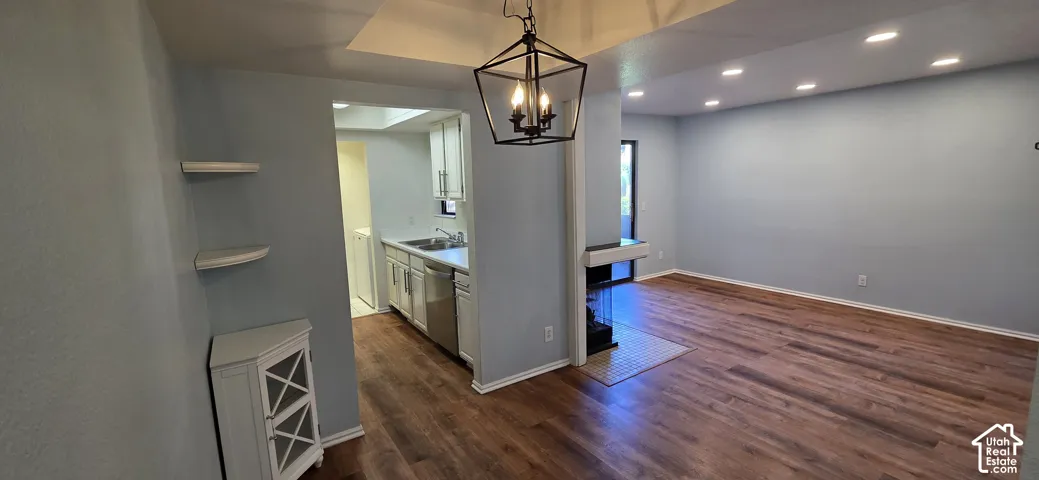 Open-concept interior featuring wood-finish flooring, recessed lighting, a geometric pendant light, a two-sided fireplace, and built-in wall shelving