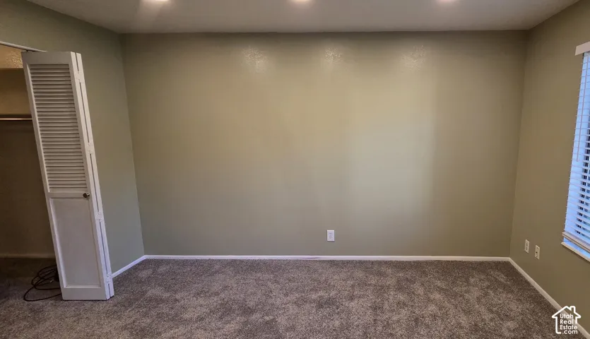 Neutral wall coloring, carpeting, recessed ceiling lighting, louvered bi-fold closet door, and window with blinds