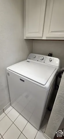 Utility area featuring white ceramic floor tiling, upper cabinetry, and a top-load washing machine