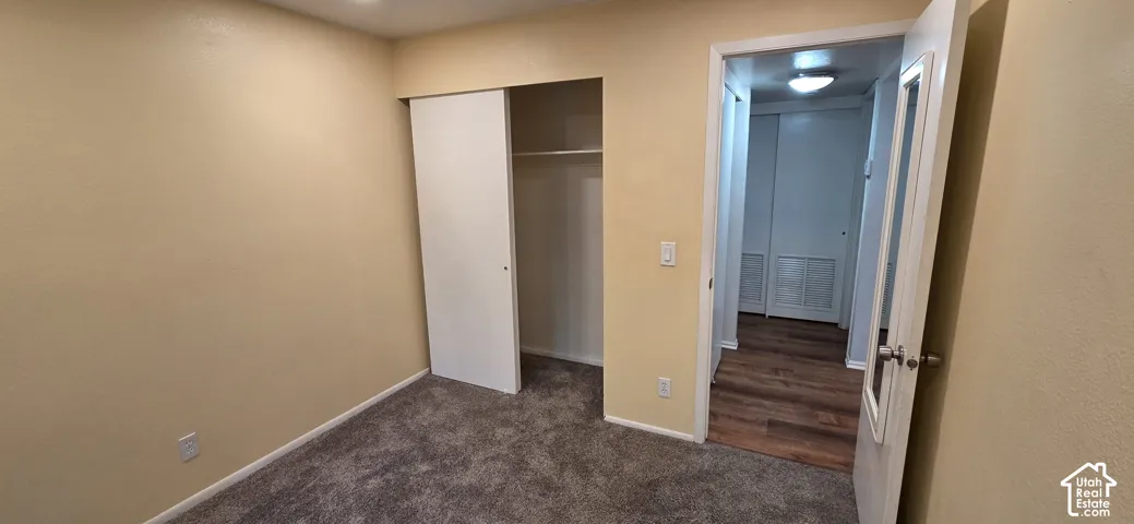 Room featuring neutral wall finishes, grey carpeting, and a built-in closet with a sliding door