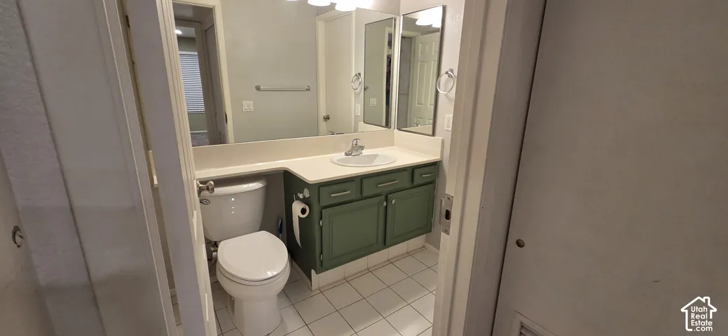 Bathroom featuring a vanity with a solid-surface countertop, an integrated sink, satin-finish cabinetry, a large wall-mounted mirror, and ceramic tile flooring