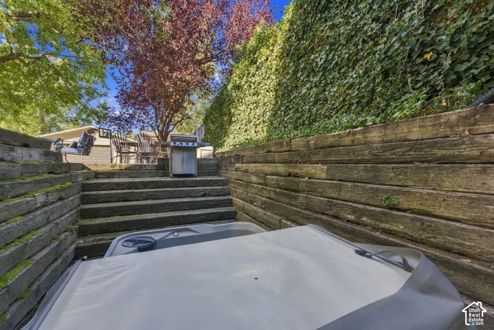 Tiered outdoor space featuring timber retaining walls, stone-stepped stairs, and vertical greenery