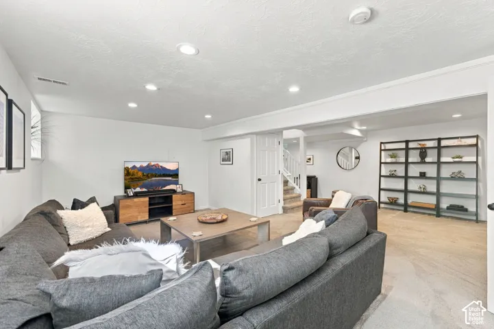 Open-concept room featuring recessed lighting, neutral carpeting, and built-in floor-to-ceiling metal shelving
