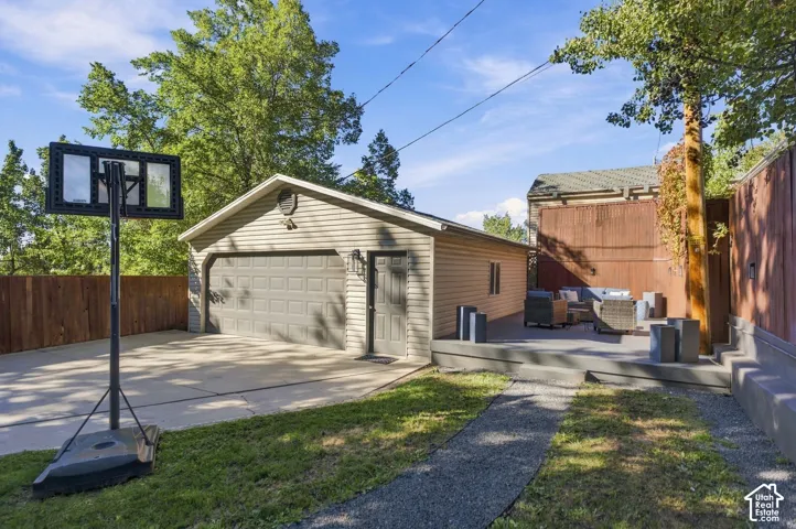 Detached garage with horizontal siding, concrete driveway, and elevated patio space