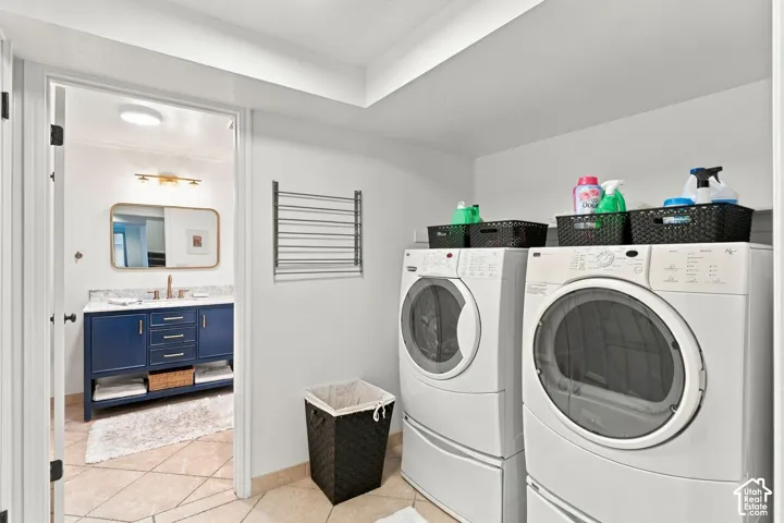 Laundry area featuring a wall-mounted drying rack and shelving, revealing a bathroom with a navy blue vanity cabinet, stone countertop, rectangular undermount sink, and brass faucet fixture