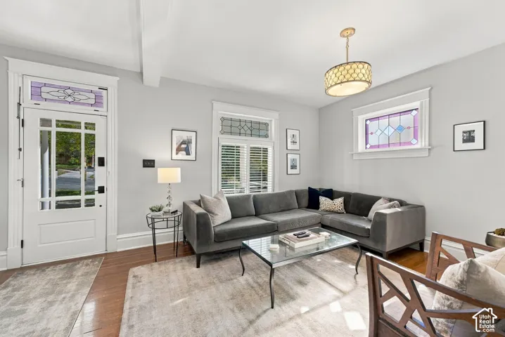 Living area featuring original hardwood flooring, leaded glass transom windows, and a drum-style pendant light fixture