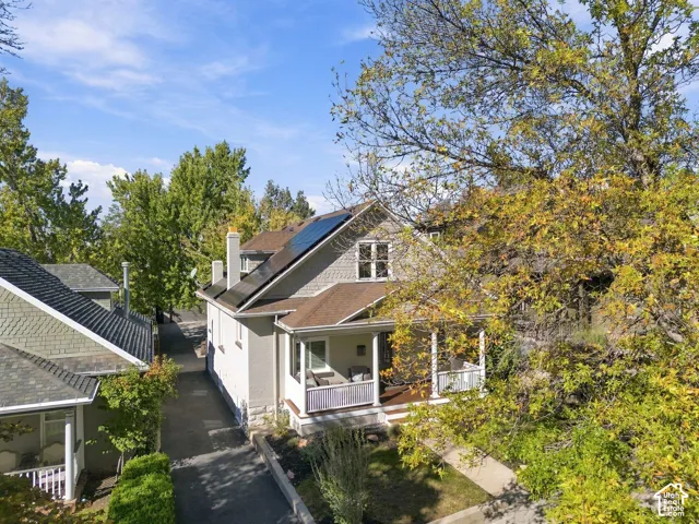 Craftsman-style exterior featuring shingle siding, a covered front porch with decorative railings, a concrete driveway, and roof-mounted solar panels