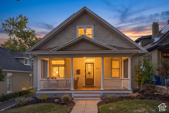 Craftsman-style exterior featuring painted brick masonry, shake siding, a covered front porch with classical columns, and an integrated transom window above the main entry