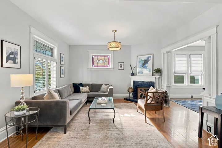 Living area featuring wood-finish flooring, a fireplace with dark tile surround, stained glass windows, and architectural columns