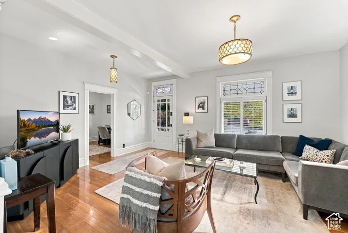 Living area featuring hardwood flooring, decorative stained glass window transoms, drum-style pendant lighting, and a front entry door with glass paneling