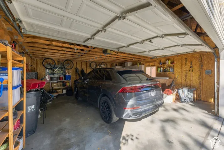 Attached garage featuring a concrete floor, exposed wood framing, and a sectional overhead door