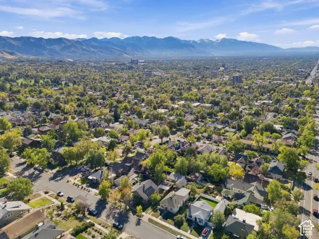 Aerial perspective featuring an established neighborhood with mature trees and a prominent mountain range backdrop
