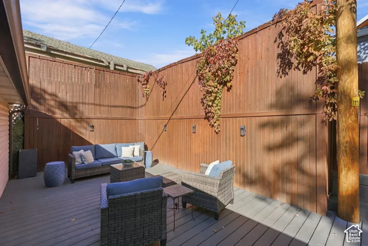 Private outdoor deck featuring grey composite decking, vertical wood privacy fencing, and wall-mounted exterior lighting fixtures