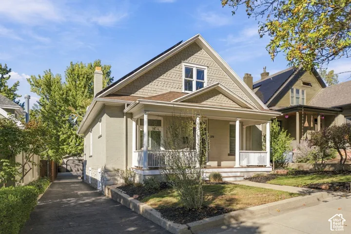 Craftsman-style exterior featuring a covered front porch with columns, decorative shingle siding, a stone foundation, and a private driveway