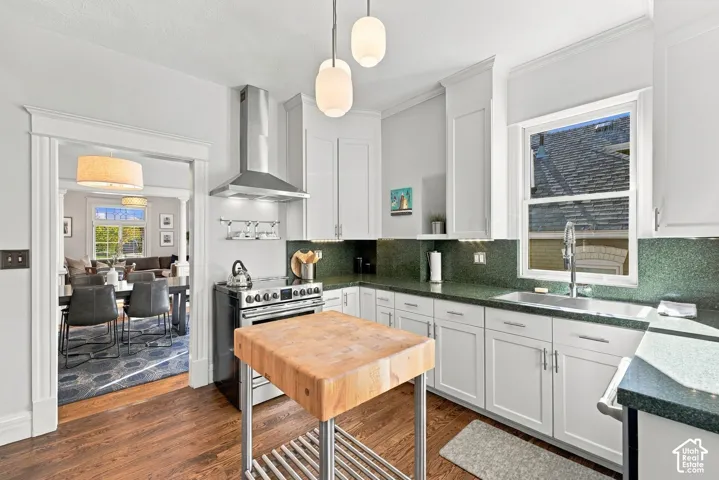 Kitchen featuring white cabinetry, solid-surface countertops, stainless steel range with matching hood, and wood-finish flooring