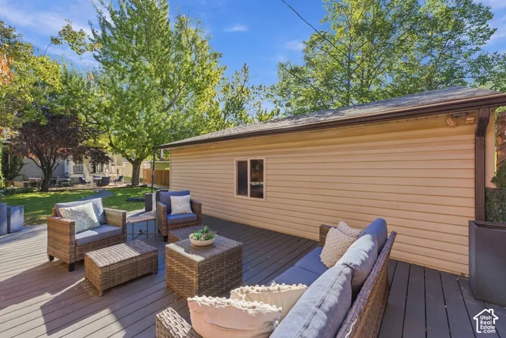 Expansive dark-toned deck featuring horizontal composite-style planks, mature landscaping, and mature trees