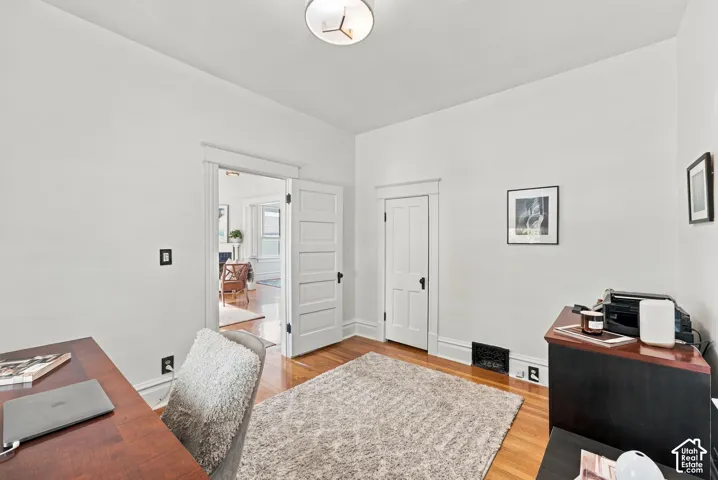 Room featuring wood-finish flooring, white walls, traditional wood door casings, a five-panel interior door, and a flush-mount circular ceiling light fixture