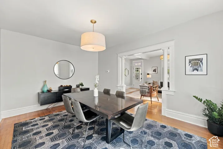 Dining room featuring hardwood flooring, a drum pendant light fixture, and an ornate white columned entryway