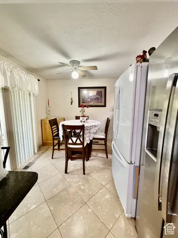 Tiled flooring laid on a diagonal pattern, ceiling-mounted paddle fan with integrated light fixture, and floor-to-ceiling sliding glass doors