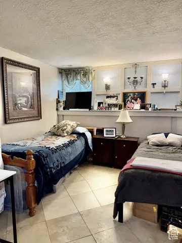 Room featuring large format tile flooring, built-in wall paneling with integrated shelving, and dual decorative wall-mounted lighting fixtures