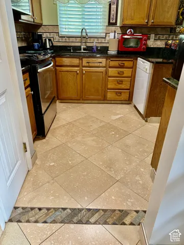 Kitchen featuring wood cabinetry, stone-finish countertops, tile flooring with decorative border inlay, and a gooseneck faucet