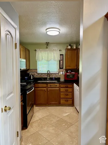 Kitchen featuring wood cabinetry, stone-finish countertops, tile flooring laid on a diagonal, decorative tile backsplash, and built-in appliances