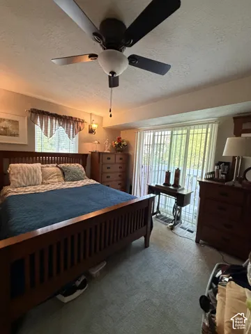 Bedroom featuring a ceiling fan with integrated lighting, wall-mounted sconce, and sliding glass doors with access to an exterior deck