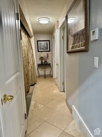 Hallway featuring diagonal tile flooring, multi-panel doors with brass-finish hardware, and a flush-mount dome light fixture