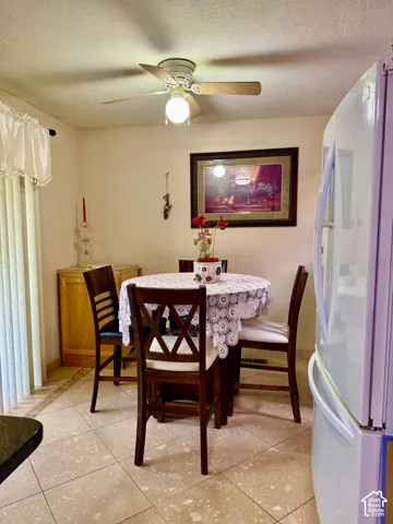 Ceramic tile flooring, neutral wall tones, white refrigerator, and ceiling fan fixture