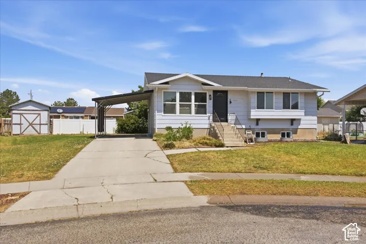 Single-story exterior featuring horizontal siding, a covered carport, concrete driveway, and a detached storage shed