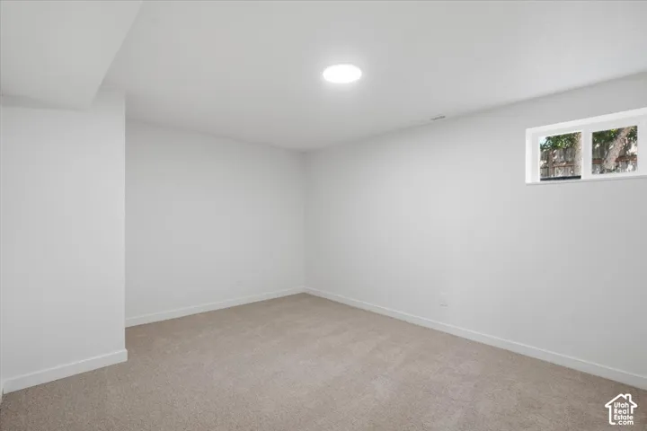 Neutral interior room featuring neutral-tone carpeting, smooth white walls, recessed ceiling lighting, and a horizontal window